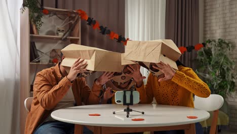family in halloween paper bag costumes recording video