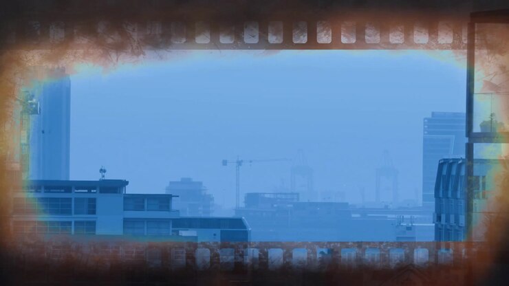 Bordo di pellicola bruciata che sfarfalla intorno a uno skyline urbano statico, evocando un'atmosfera nostalgica