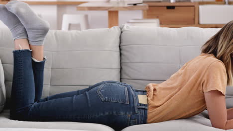 mujer relajada acostada en el sofá en casa trabajando en una computadora portátil