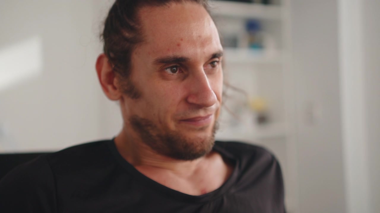 Uomo che sorride e riflette in un ambiente interno luminoso