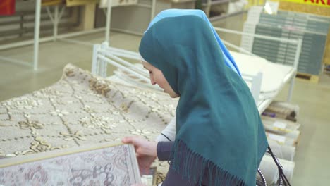 two young muslim women in hijab choose a rug in the store close up