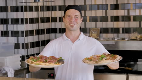 Glücklicher-Koch,-Der-Pizzas-Zeigt-Und-Im-Restaurant-1-In-Die-Kamera-Lächelt