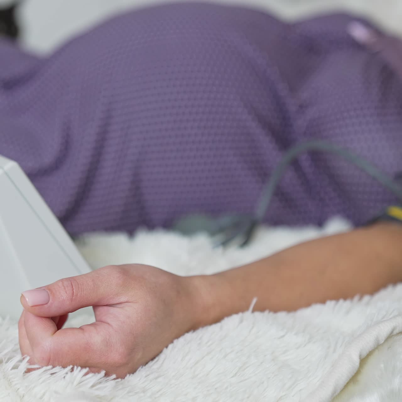 Zwangere vrouw meet haar bloeddruk terwijl ze rustig op bed ligt. Zwangere vrouw wazig op bed. Zwarte kat loopt op de achtergrond