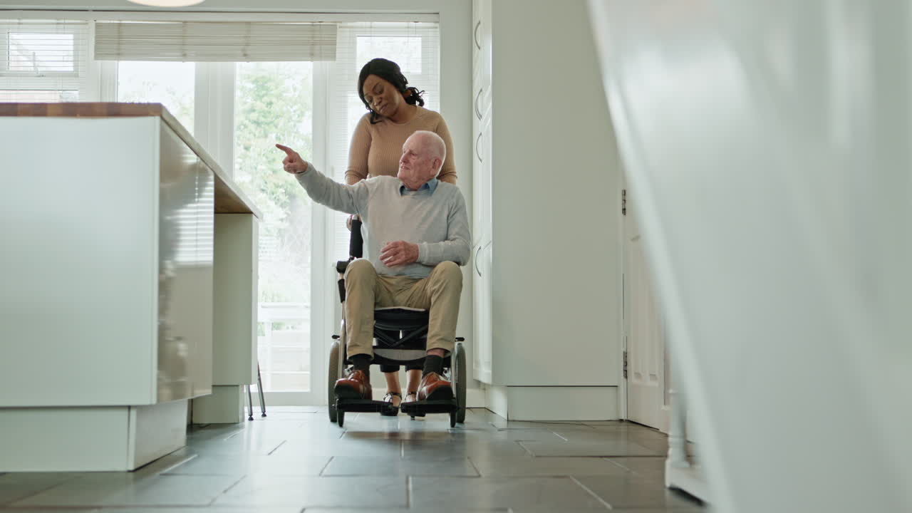 Elderly Man in Wheelchair Assisted by Caregiver