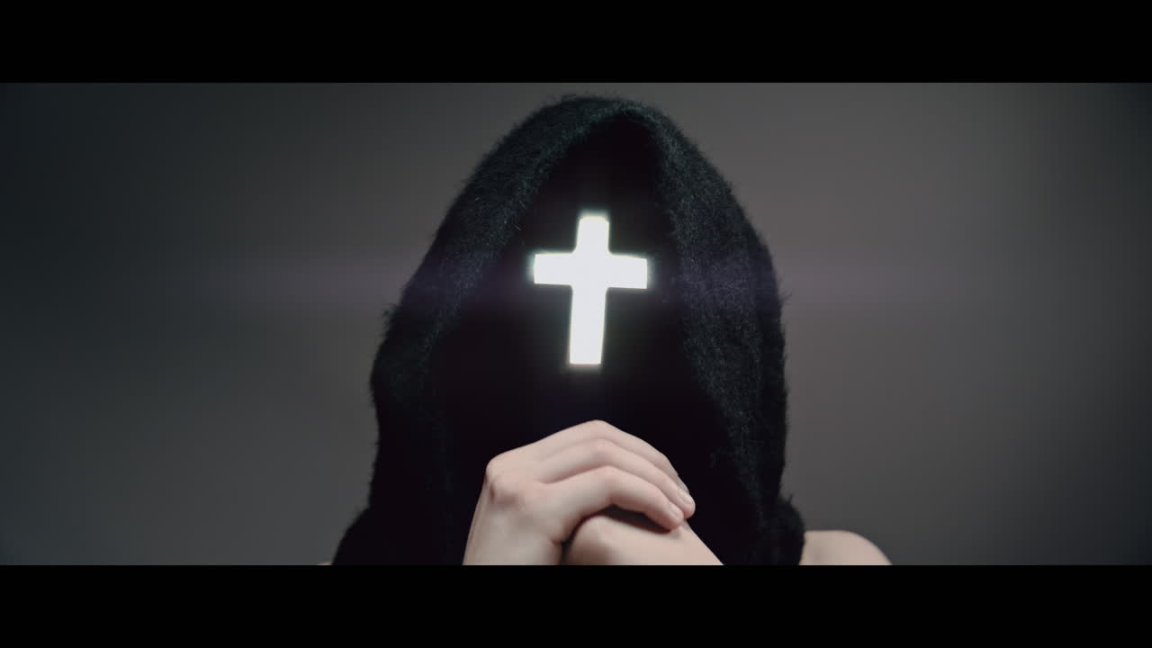 Masked man with cross of light glowing on his face moves his head up