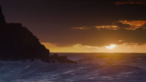 the sun sets as ocean waves break against hawaiian shores