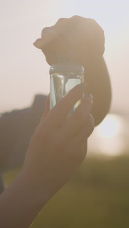 a woman opens a small foaming bottle under the warm sunlight, while a young child eagerly watches beside her, excitement evident on his face. a tender, joyful moment bathed in a golden glow