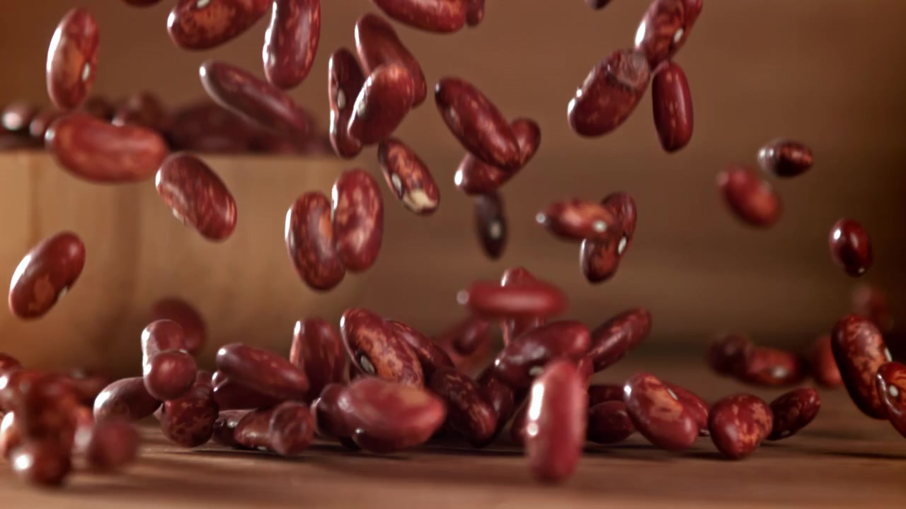 Red Kidney Beans Falling in Slow Motion onto a Wooden Surface
