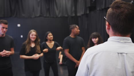 teacher with drama students at performing arts school in studio improvisation class