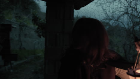 scared woman explores a house in the countryside at night with a lantern in hand