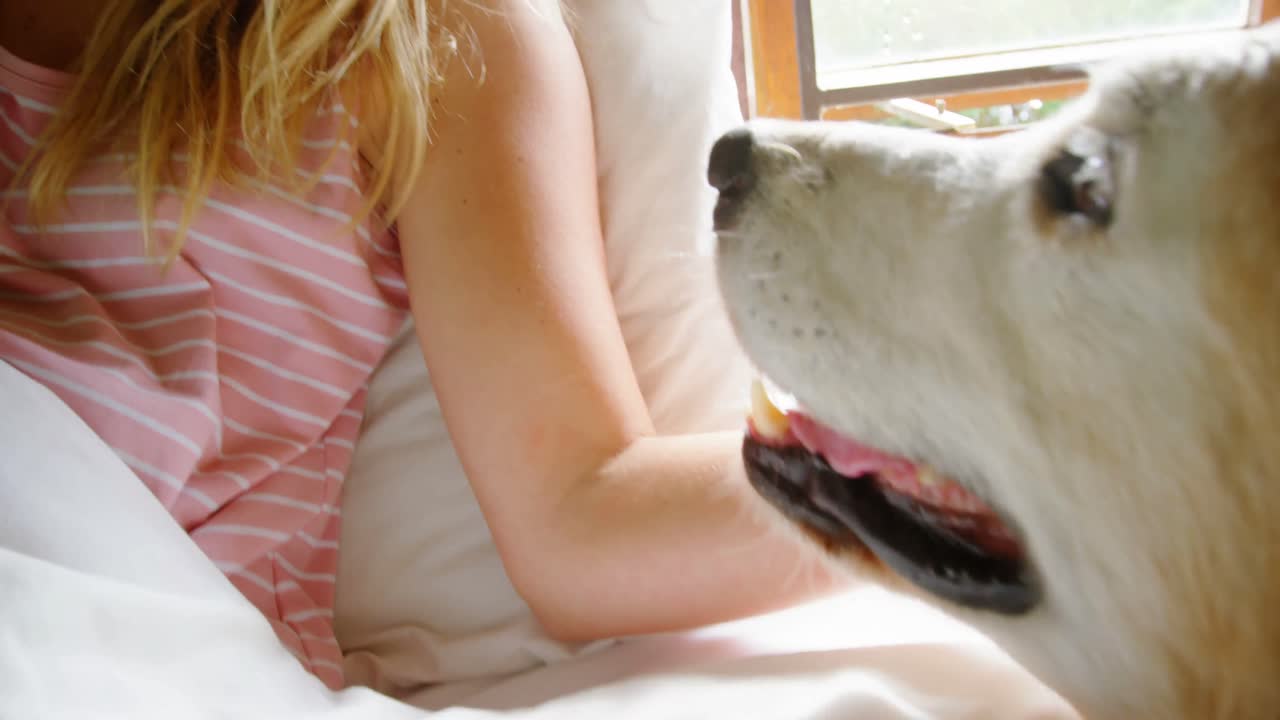 침대 4k에 그녀의 개와 함께 앉아있는 아름다운 여자