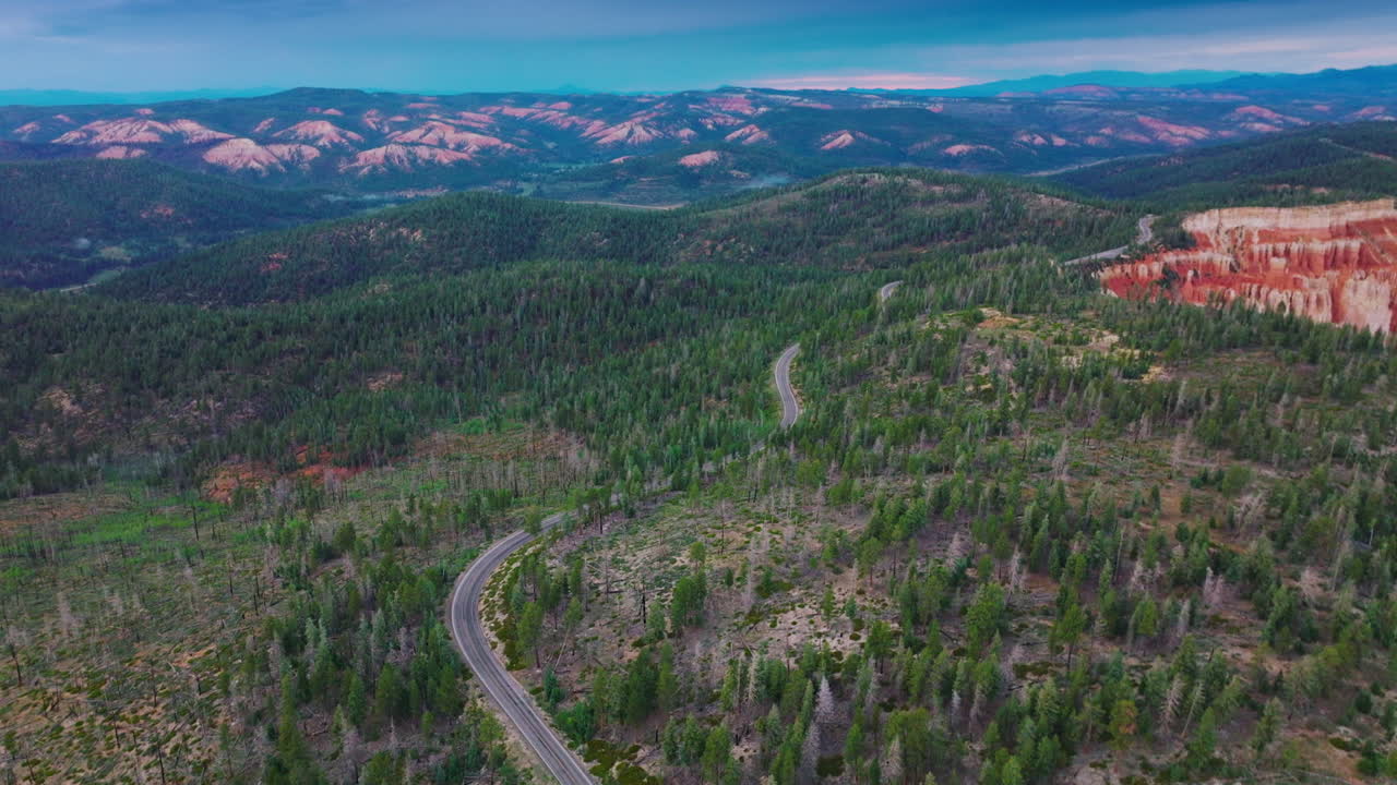 Wavy motorway passing the pine woods covering the mountains. Pleasing scenery of beautiful canyons of Utah, USA. Top view.