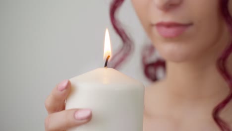 mãos femininas com esmalte segurando uma vela acesa