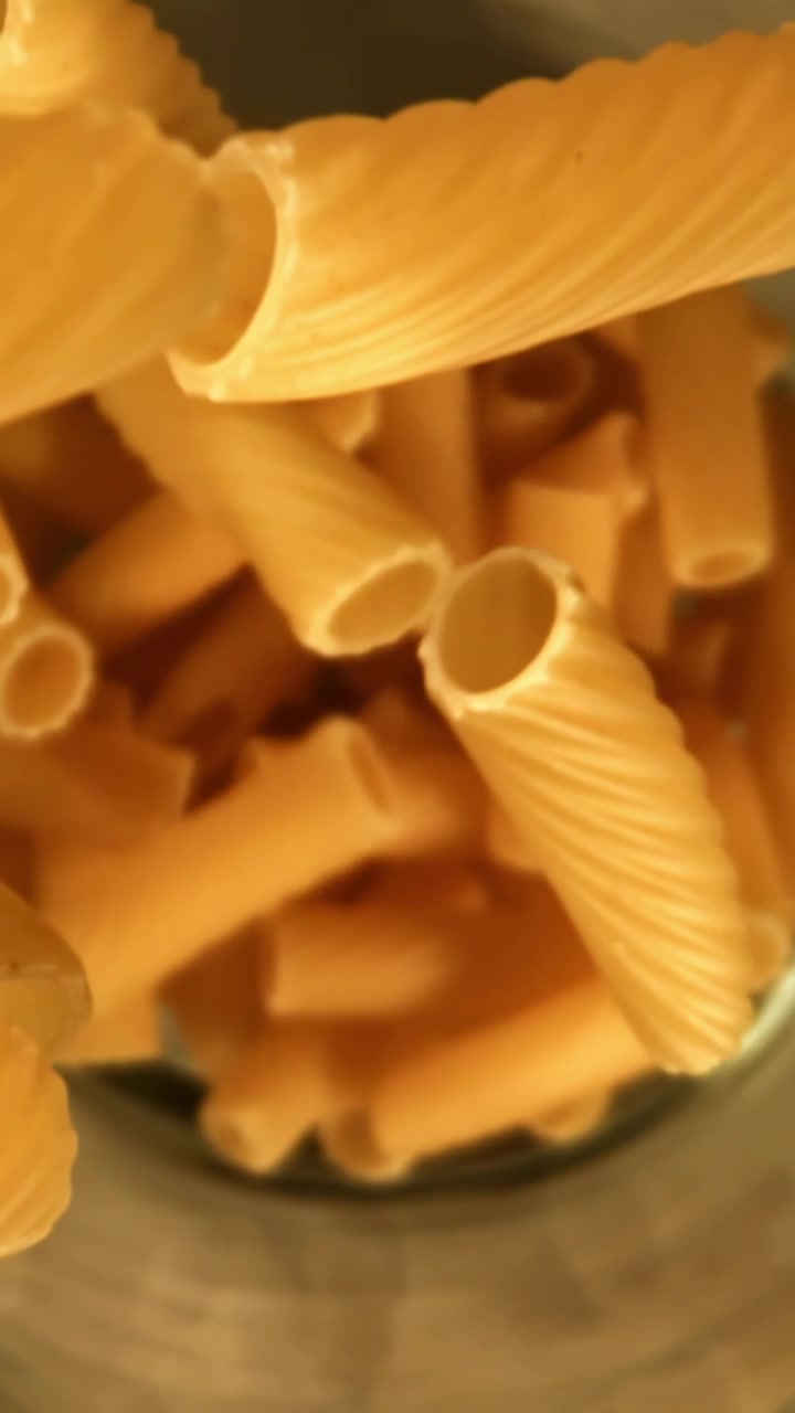 Rigatoni crudi che cadono in un contenitore