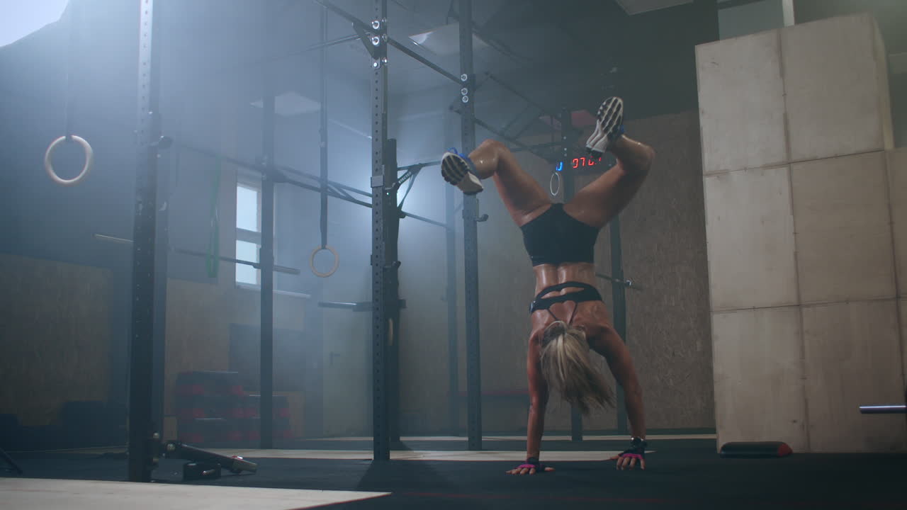 un sollevatore di pesi femminile esegue un sollevamento di barra in una palestra buia. una donna che solleva una pesante barra sopra la sua testa