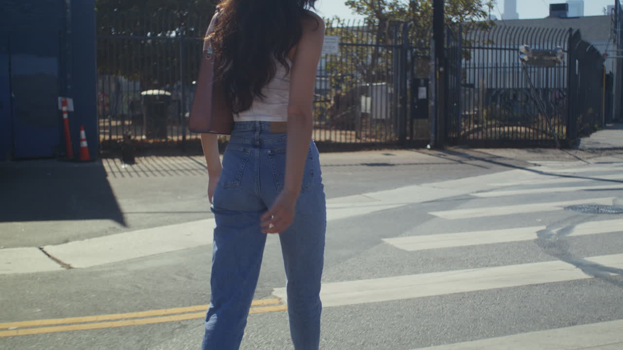 Primo piano di una donna sconosciuta che attraversa la strada. Una donna elegante dai capelli lunghi cammina sulle strisce pedonali.