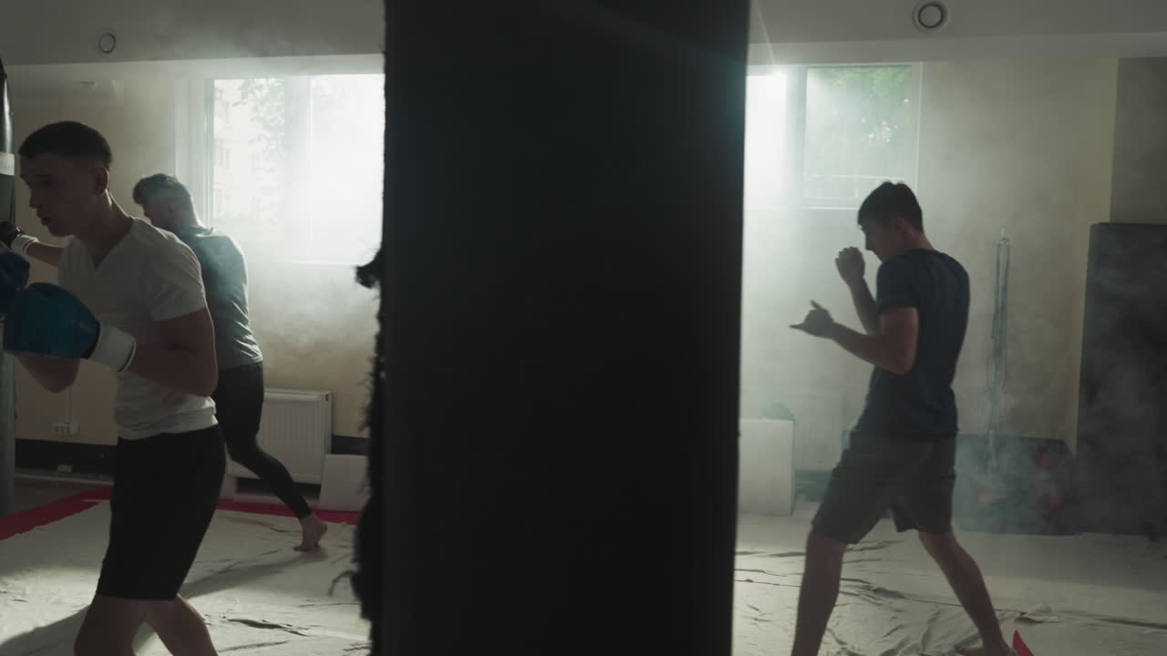 체육관에서 부이에 부히는 전투기 훈련. 프로 스포츠 선수 팀은 스모키 스포츠 클럽의 느린 동작에서 주먹과 발로 부히고 운동합니다.