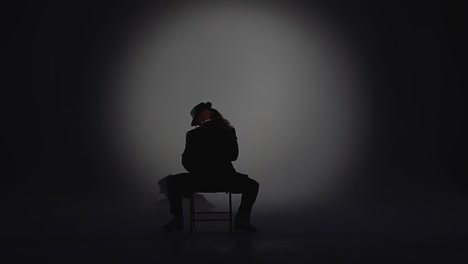 dramatic silhouette of a man seated in a spotlight