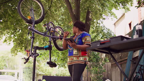 woman with device fixing bicycle in yard