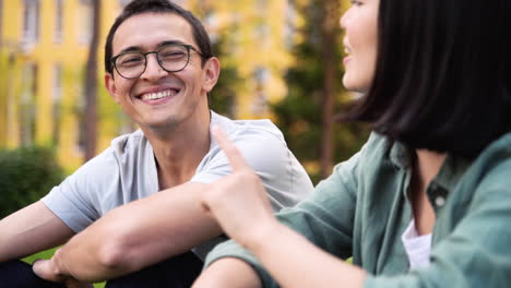 two japanese friends talking and laughing while sitting together outdoors