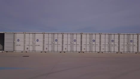 slow panning shot of a small line of open and closed shipping containers in a row