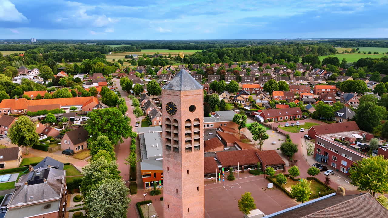 Tall brick clock tower of Saint Lawrence Church. Picturesque scenery of Vierlingsbeek, Netherlands with lush grenery at backdrop