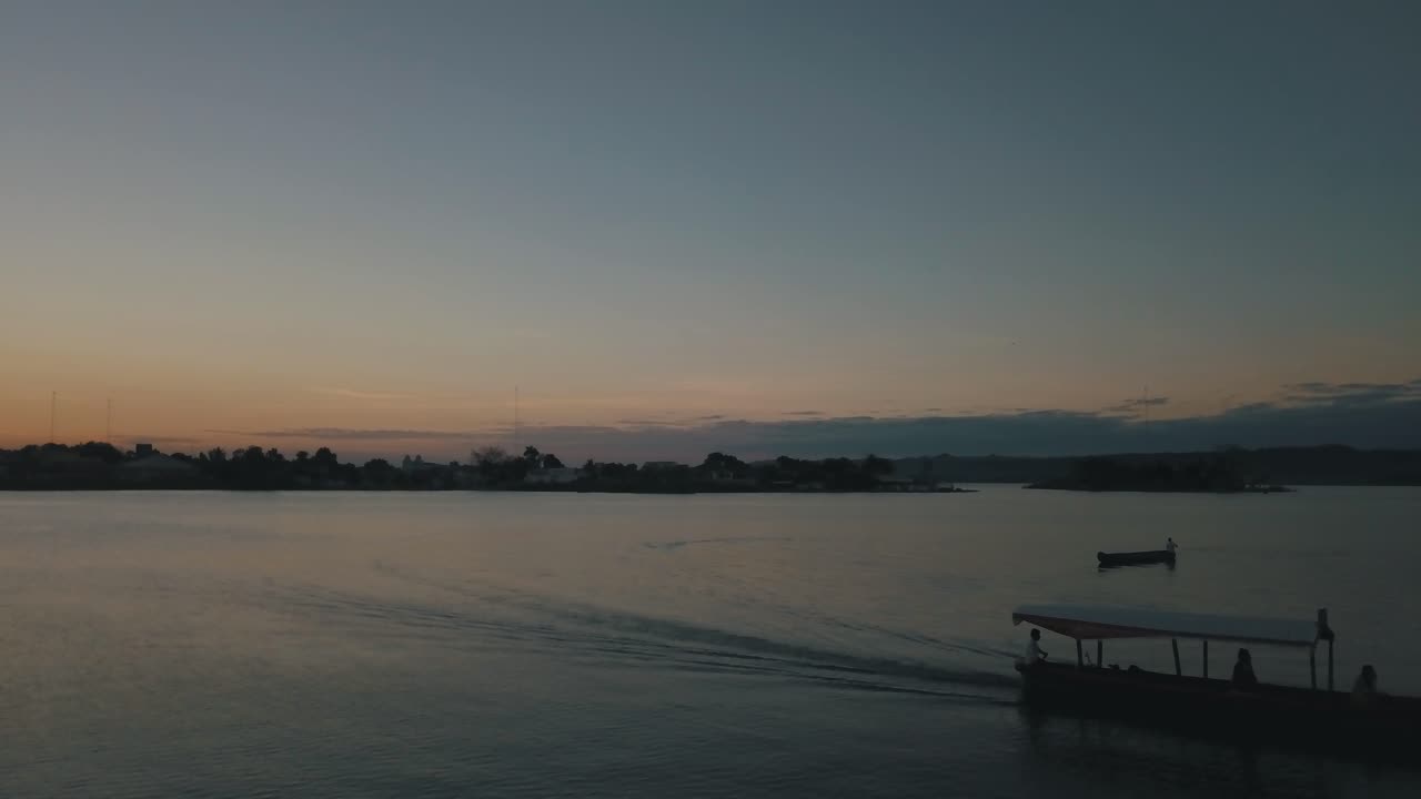 Sunset drone aerial of a boat driving through the lake of Flores Peten, Guatemala