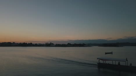 sunset drone aerial of a boat driving through the lake of flores peten, guatemala