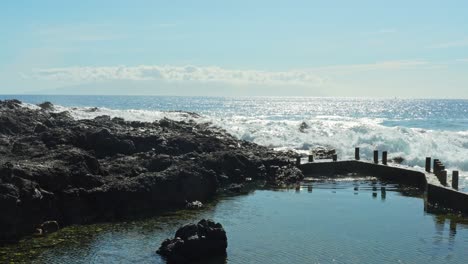 powerful waves crashing over tenerife's volcanic rock pools