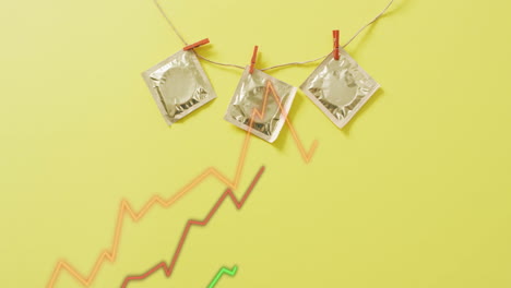 condoms hanging on string with clothespins over rising graph animation on yellow background