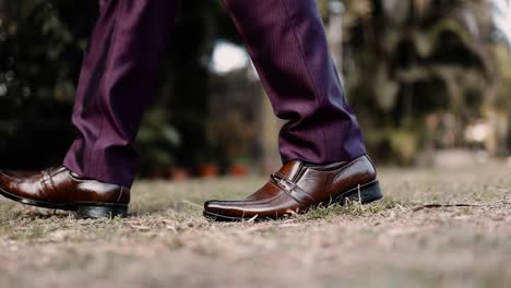 Side-view-of-a-man-wearing-formal-shoes-and-elegant-dress-slacks,-walking-foot-and-legs-close-up