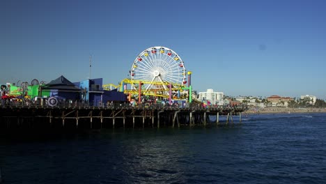 Santa-Monica-Pier-Riesenrad-Und-Achterbahn,-Die-Sich-Nicht-Bewegen,-Mit-Blick-Auf-Den-Pazifischen-Ozean-Und-Den-Strand-Im-Hintergrund