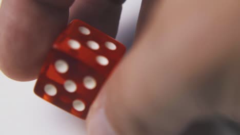 man-shows-stylish-dices-against-light-surface-macro