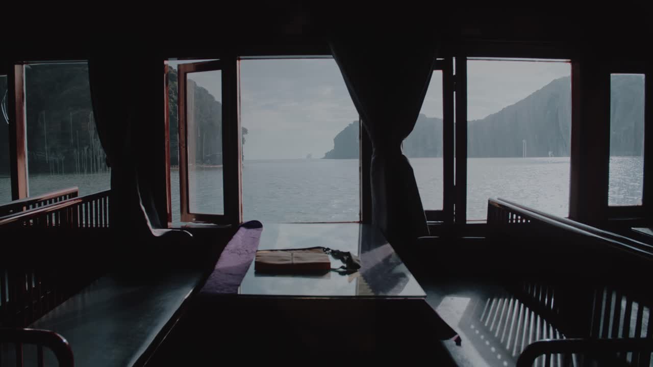mesa y sillas vacías junto a una ventana en un ferry que navega a lo largo de la bahía de lan ha en vietnam