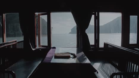 empty table and chairs by a window on a ferry sailing along lan ha bay in vietnam