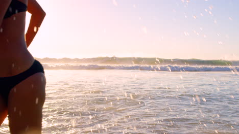 woman running in the ocean at sunset