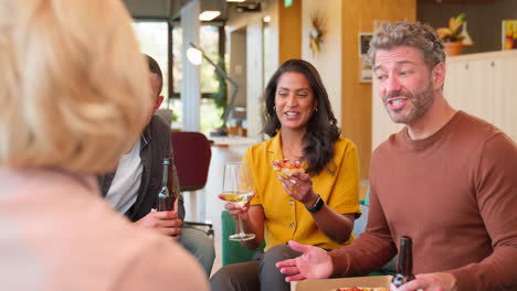 en una reunión informal del personal en la oficina con pizza para llevar haciendo un brindis con bebidas