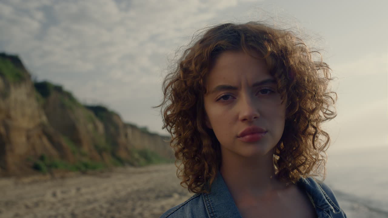 mujer enfocada en primer plano mirando hacia la playa. cara de chica seria posando ante la cámara
