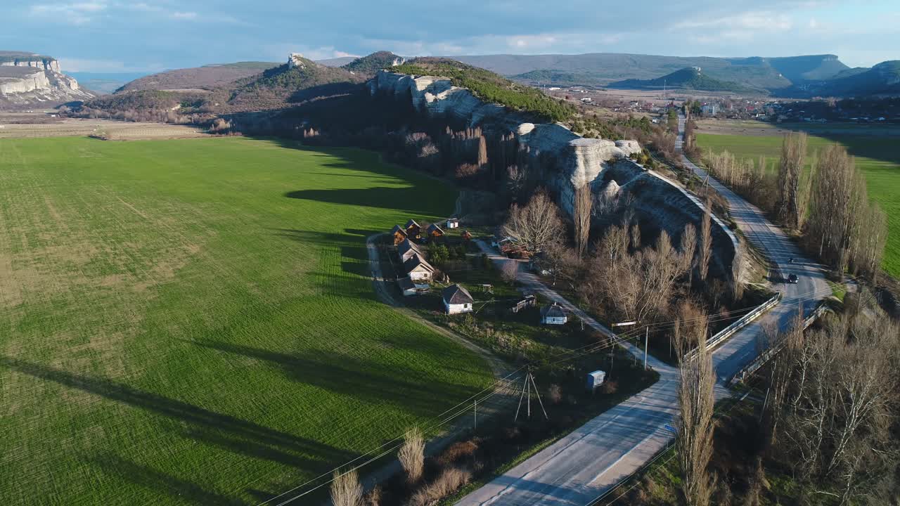 vista aérea de un pintoresco valle con montañas, campos y casas.