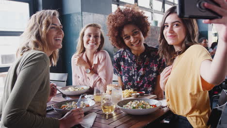 four female friends posing for selfie in restaurant before eating meal