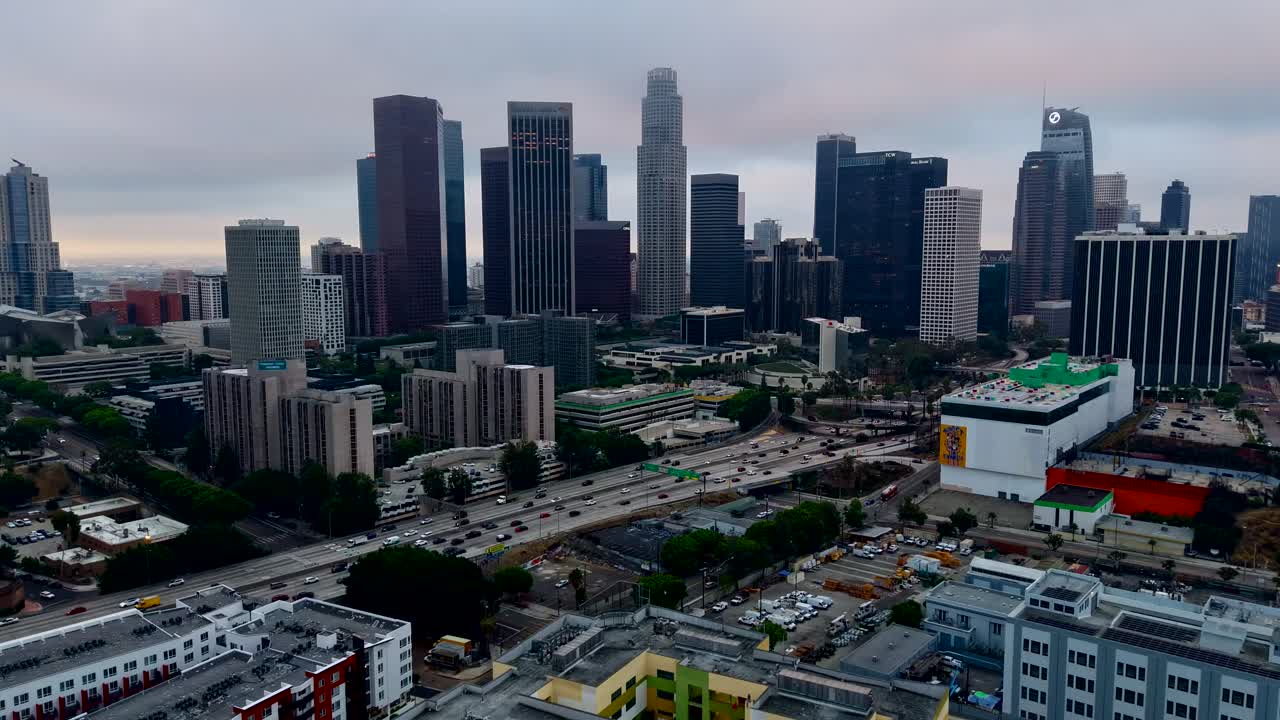 Timelapse video of the Los Angeles skyline on a cloudy morning. A dark, gloomy scene of traffic flowing into the city