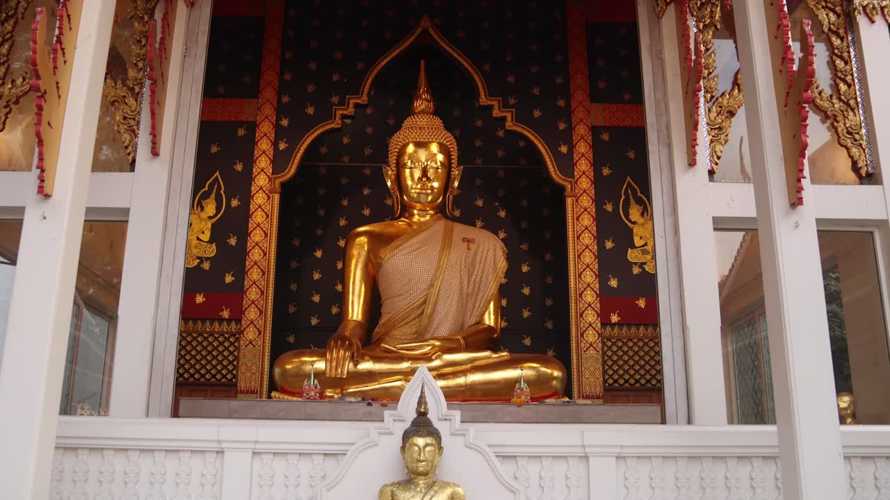 estatua dorada de buda en meditación frente a un templo en el casco antiguo de rattanakosin de bangkok, tailandia
