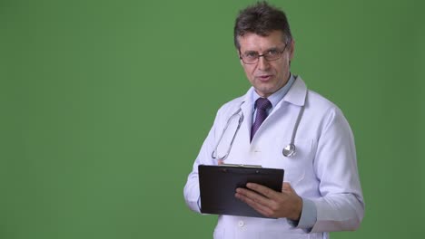 hombre maduro y guapo médico contra fondo verde