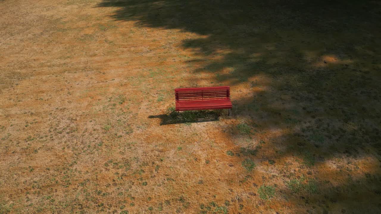 Empty Red Wooden Bench In The Sunny Field Of A Park. Aerial Drone Shot