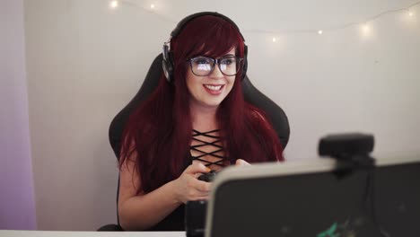 young girl with red hair is playing games on the console using gamepad and cheering