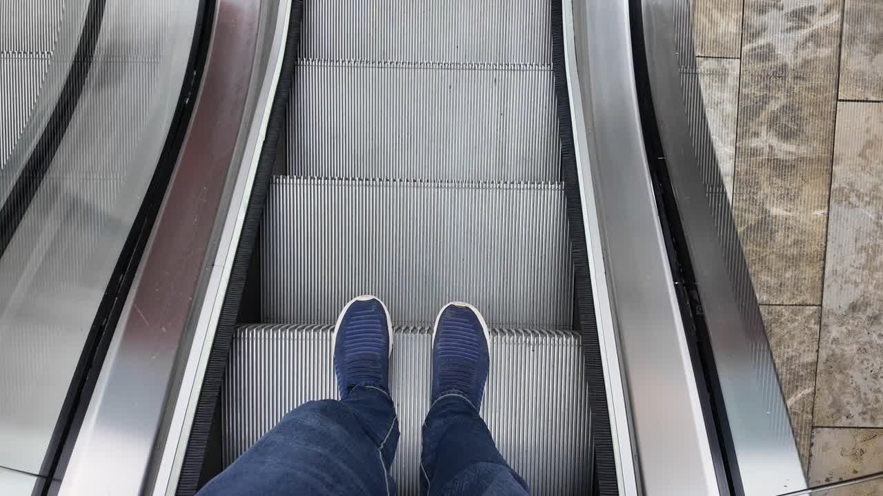 Person står på en kørende rulletrappe