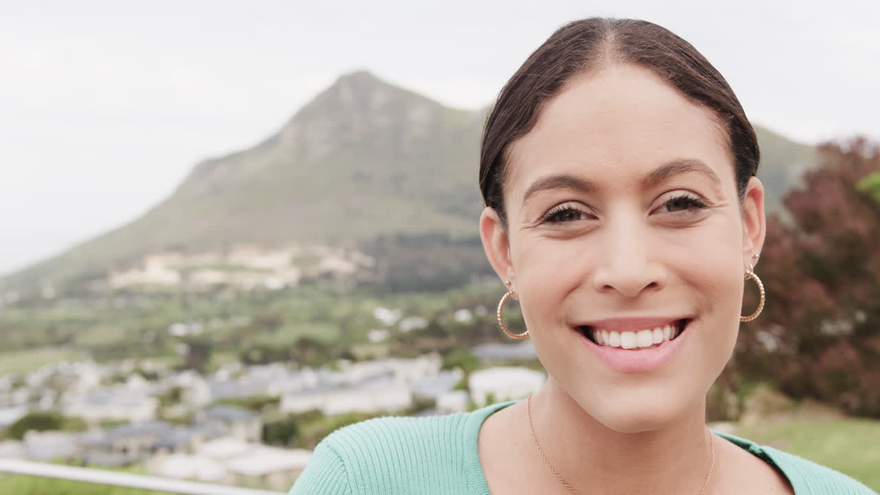 retrato de una mujer biracial feliz de pie en el balcón de su casa, espacio de copia, cámara lenta