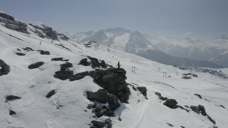 person standing on a cliff overlooking a snow-covered mountain range