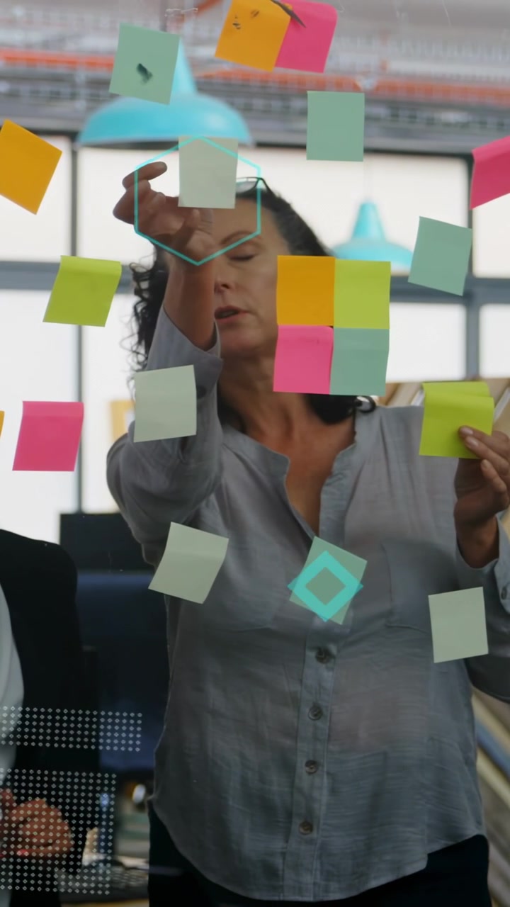 Vídeo vertical: Descascando notas adesivas, colocando-as no vidro para planejamento de escritório, com sobreposições cintilantes