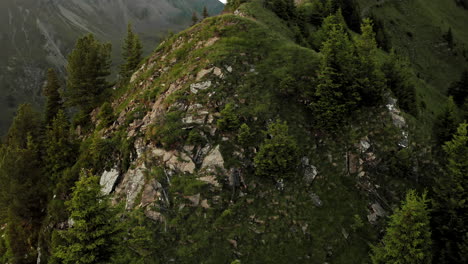 Vista-Aérea-De-Drones-De-Un-Excursionista-Profesional-Solitario-Con-Una-Bolsa-De-Trekking-Escalando-En-La-Cima-De-La-Montaña